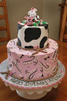 a pink and black birthday cake with a cow on top