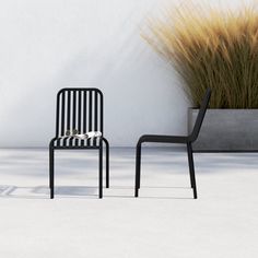 two black and white chairs sitting next to each other near a potted grass plant