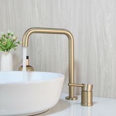 a bathroom sink with gold faucet and white bowl