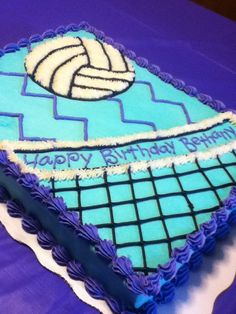 a volleyball themed birthday cake with blue icing and white frosting on purple table cloth