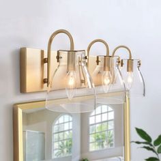 a bathroom vanity light with three lights on it and a mirror in front of it