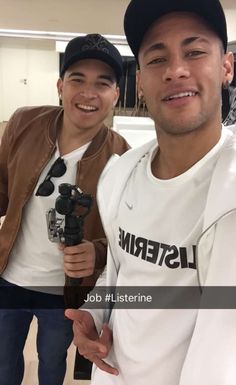 two young men are smiling and posing for a photo together, one is holding a microphone