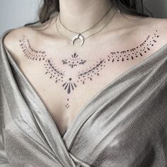 a woman with tattoos on her chest is wearing a silver dress and has a crescent