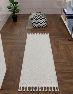 a large white rug sitting on top of a wooden floor next to a potted plant