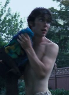 a shirtless young man holding a stuffed animal in his hand and looking at the camera