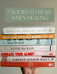 a person holding a stack of books with the title 7 books to read when healing