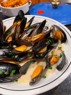 a white plate topped with mussels covered in sauce