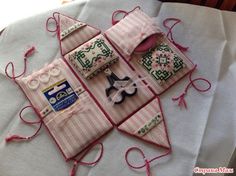 some pink and white items are on a table with red thread, scissors and sewing needles