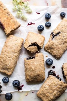 blueberry scones on parchment paper with flowers and berries around them, ready to be eaten