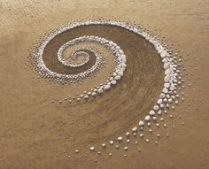 a spiral made out of rocks in the sand