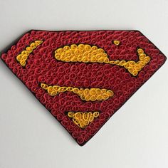 a close up of a superman logo made out of plastic beads on a white surface