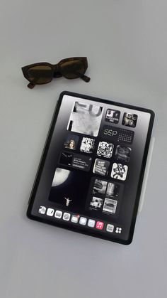 an ipad with sunglasses on top of it next to a pair of black eyeglasses