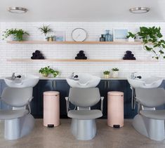 a bathroom with three sinks and two stools in front of the sink is surrounded by plants