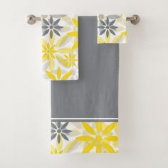 two yellow and gray towels hanging on a towel rack in front of a white wall