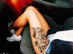 a woman sitting in the back seat of a car with flowers on her arm and legs