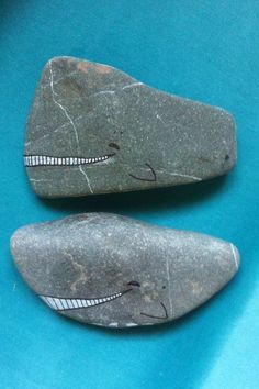 two rocks with faces painted on them are sitting next to each other in the middle of a blue surface