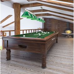 a pool table in the middle of a room with wood floors and exposed ceiling beams