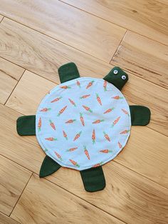 a turtle shaped rug with carrots on it's back sitting on the floor