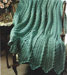 a green crocheted blanket sitting on top of a chair