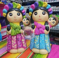 two figurines in the shape of children with colorful hair are on display at a store