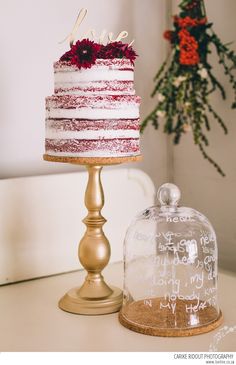 a red and white cake sitting on top of a table next to a glass dome