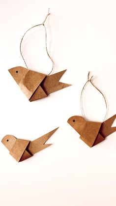 three origami birds are hanging from twine