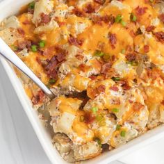 a casserole dish with potatoes, bacon and green onions in it on a white table