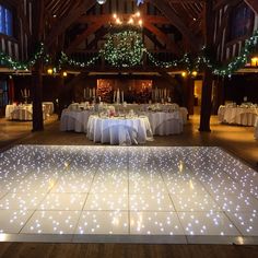 a large dance floor with lights on it in a room filled with tables and chairs