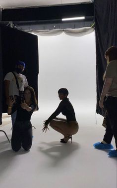 three people standing in front of a white backdrop with one person kneeling on the ground