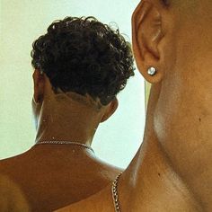 a man with no shirt is looking at his reflection in the mirror while wearing a silver necklace