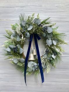 a christmas wreath hanging on the side of a wall with a bell and evergreens