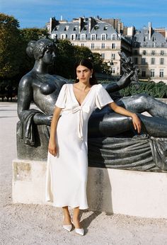 The Brunello Dress in ivory is a full length short-sleeve v-neckline dress featuring a fixed bow at the bust, fluttery sleeves, and size zipper closure.  Fit: True to Size. Model wears size small. Sizing: XXS-XL Materials: 100% Polyester Satin Ciao Lucia, White Evening Dress, Instagram Dress, Satin Evening Dresses, Dinner Dress, Blue Denim Jacket, Necklines For Dresses, Polyester Satin, Sweater Sale