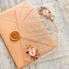 an envelope with a wax seal on it and some flowers in the middle, sitting on a wooden table