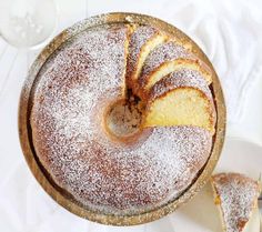 a cake with powdered sugar on top is sitting in a pan next to two slices