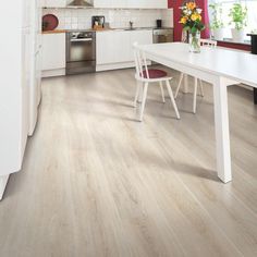 a white table and chairs in a room with red walls, hardwood flooring and cabinets