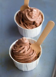 two cups filled with chocolate ice cream on top of a table