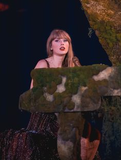 a woman standing in front of a moss covered tree