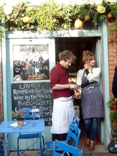 two people standing in front of a small restaurant