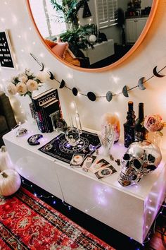 a white table topped with lots of halloween decorations next to a round mirror and lights