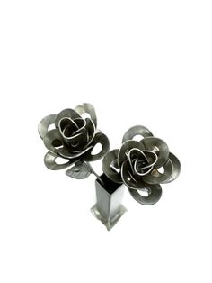 two metal flowers are sitting on top of each other in front of a white background