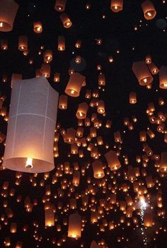 many lit up lanterns floating in the air