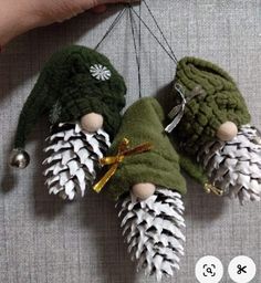 three small pine cones are hanging from a string with bells on them, and one is made out of yarn