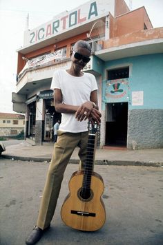 a man holding a guitar on the street