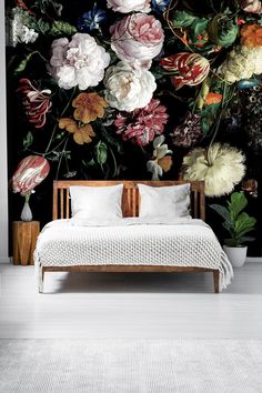 a bed sitting in front of a wall with flowers on it