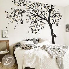 a bedroom decorated in white and black with a tree painted on the wall above the bed