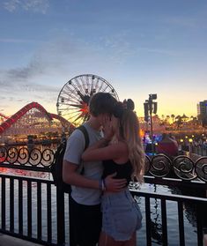 two people standing next to each other in front of a ferris wheel