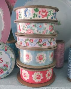 there are many different types of ribbons on the shelf in front of plates and bowls