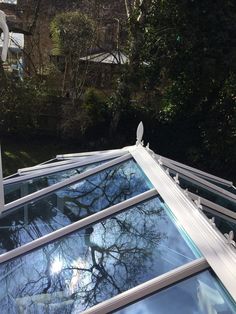 the roof of a house with trees reflected in the glass on it's side