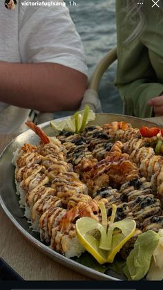 a large platter filled with food sitting on top of a table next to water