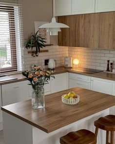 a kitchen island with two stools and a bowl of fruit on the counter top